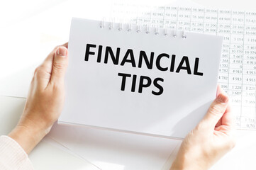 FINANCIAL TIPS word inscription on white card paper sheet in hands of a businessman. recap concept. red and white paper