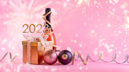 Merry Christmas and Happy New 2023  Year. Gift in a golden box, pink champagne and christmas balls...