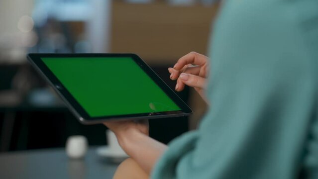 Woman hands scrolling chroma key screen at cabinet closeup. User tapping tablet