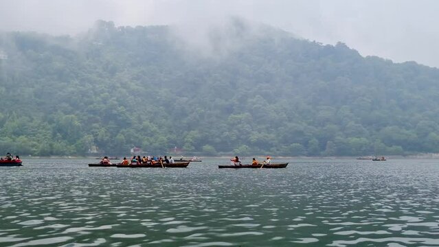 Tourists wearing red life jackets on a row boat being taking tourists for a trip along the foggy lake of bhimtal a popular hill station in uttarakhand India a beautiful destination