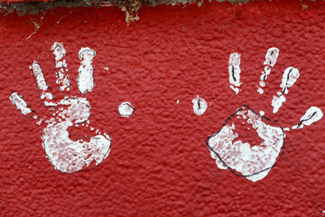  White hand prints on old red wall 