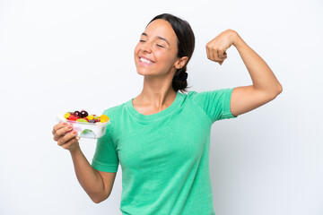 Young hispanic woman holding a bowl of fruit isolated on white background doing strong gesture