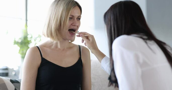 Doctor medical examination of woman throat at home