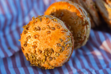 Closeup of sesame seeds encrusted in orange glaze of pumpkin flavor macaron cookies - 541989528