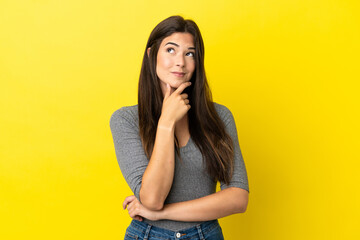 Young Brazilian woman isolated on yellow background thinking an idea while looking up