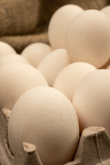 White chicken eggs in a cardboard box on the table. Close-up, selective focus