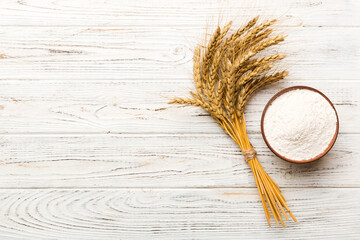 Flat lay of Wheat flour in wooden bowl with wheat spikelets on colored background. world wheat...