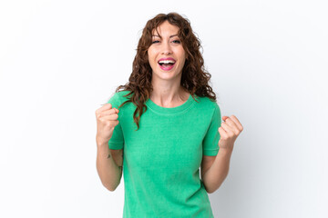 Young woman with curly hair isolated on white background celebrating a victory in winner position