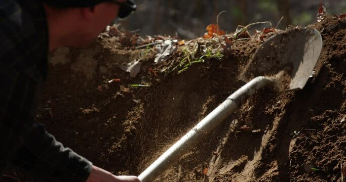 Mountain biker building dirt jumps in autumn - close up on shovel digging dirt