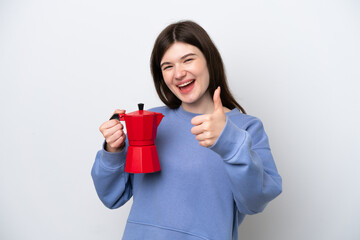 Young Russian woman holding coffee pot isolated on white background with thumbs up because something good has happened