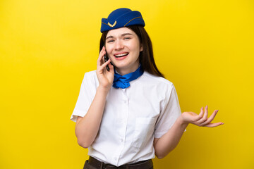 Airplane stewardess Russian woman isolated on yellow background keeping a conversation with the mobile phone with someone