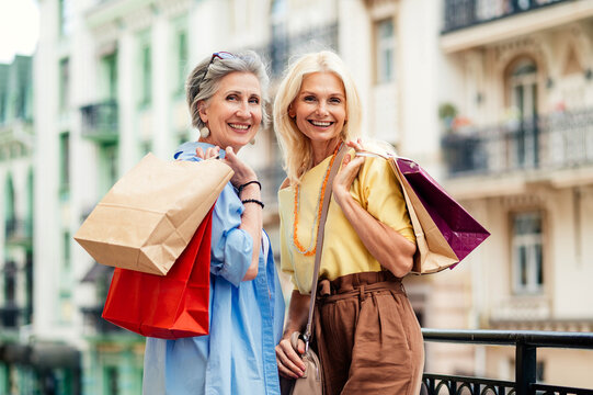 Beautiful happy senior women shopping in the city centre - Mature female adult friends with colorful stylish clothes meeting and spending time together