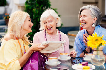 Beautiful senior women bonding at the bar - Beautiful happy senior women shopping in the city centre - Mature female adult friends with colorful stylish clothes meeting and spending time together
