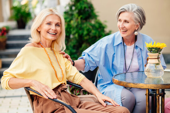 Beautiful senior women bonding at the bar - Beautiful happy senior women shopping in the city centre - Mature female adult friends with colorful stylish clothes meeting and spending time together - Powered by Adobe