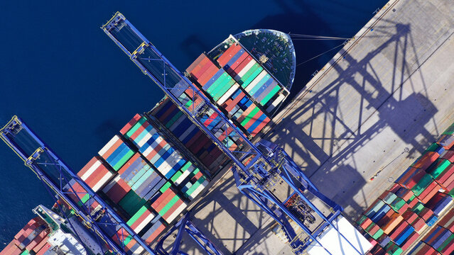 Aerial drone top down photo of container tanker ship anchored below huge cranes in loading - unloading Mediterranean terminal port