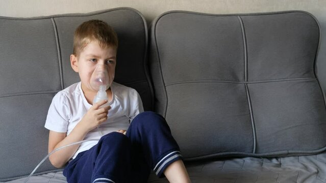 A little boy sits with an inhalation mask during cough and bronchitis