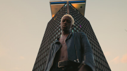 Stylish Dark Skinned Guy On Evening City Street. Behind Him Is High Rise Building.