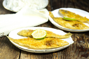 homemade fried fish lemon sole in white plate on wood table