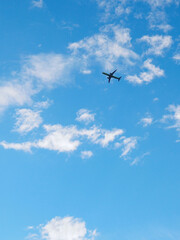 The passenger airplane is flying far away in the blue sky and white clouds. Aircraft in the air. International passenger air transportation. Vertical illustration