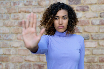 Beautiful mexican woman with curly hair gesturing stop