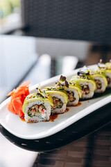 Sushi with avocado and smoked salmon on a white plate, decorated with herbs and ginger. Restaurant concept.