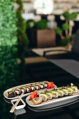 Sushi with avocado and smoked salmon on a white plate, decorated with herbs and ginger. Restaurant concept.