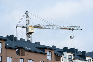 A modern house. Black metal tile roof. A construction crane is in the background