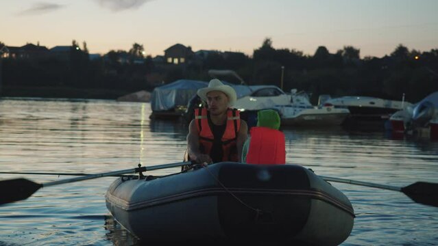 Father and son sail at evening on an inflatable boat