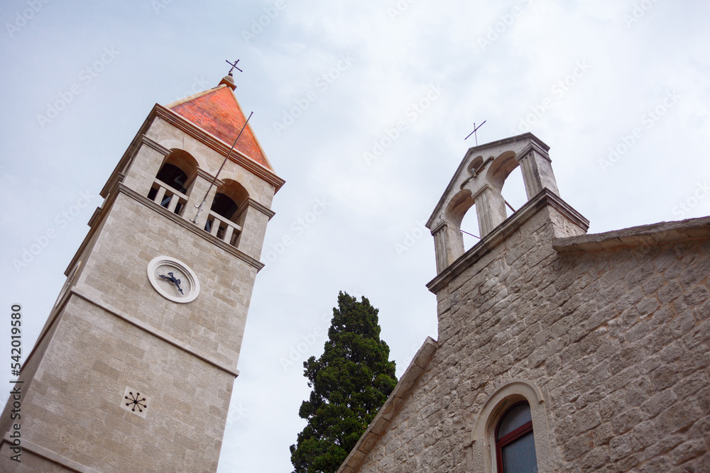 Wall mural Medieval belfry and steeple . Church of the Assumption of the Blessed Virgin Mary in Slatine Croatia . Church tower with clock