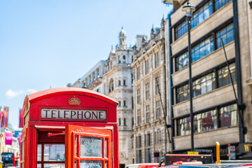 Fototapeta na wymiar European red telephone phone box booth closeup with opened door in London, United Kingdom at Piccadilly circus street in summer