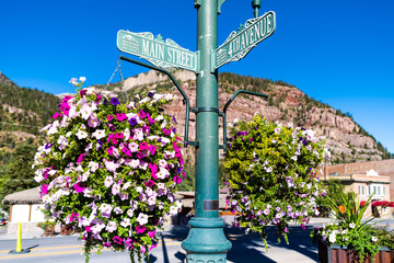 Ouray, Colorado small mining town in Rocky mountains with main street 4th avenue sign by calibrachoa flowers in hanging basket decoration in summer