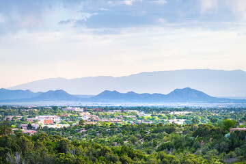 Fototapeta premium Sunset in Santa Fe, New Mexico skyline with golden hour light, summer plants by cityscape buildings with Sangre de Cristo mountains silhouette