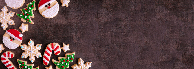 Cute Christmas cookie corner border. Above view on a dark stone background with copy space. Holiday...