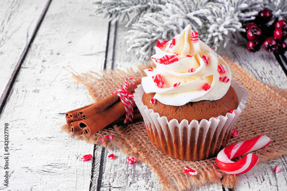 Aufkleber christmas candy cane cupcake with creamy frosting. close up with snowy branches on a rustic white wo