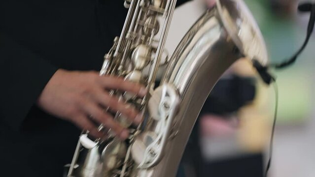 Close-up of the hands of a saxophonist who performs his part on a musical instrument.