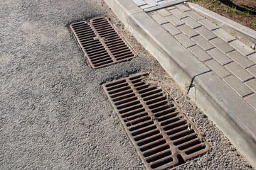 Obraz premium Long sewer grate on gray asphalt closeup