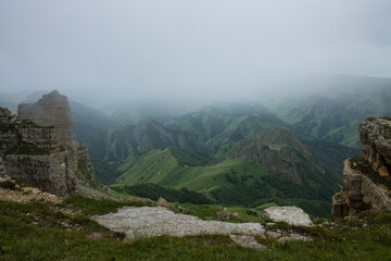 Fototapeta na wymiar Sharp rocks on the Bermamyt mountain plateau on a cloudy summer day and a hazy haze blurred on the horizon and a space for copying in Karachay-Cherkessia in the North Caucasus