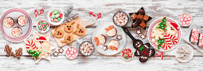 Cute Christmas sweets and cookie table scene. Overhead view on a rustic white wood banner...