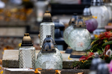 Candles and flowers on graves in the cemetery during the All Saint's Day. Taken during the day, natual light.