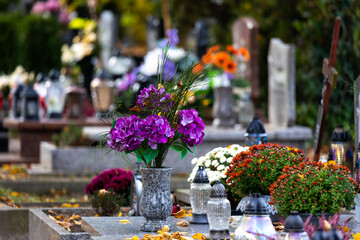 Candles and flowers on graves in the cemetery during the All Saint's Day. Taken during the day,...