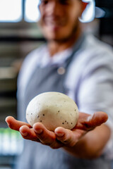 person holding a bowl of eggs. dough balls. person holding dough ball. kneading. cook showing his work. displaying a sourdough. sourdough for pizza. human hands kneading sourdough for pizza.