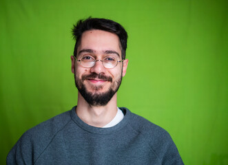 Young man with casual clothes, posing on green background