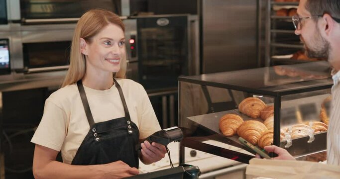 Man customer using a smartphone paying for order in a bakery shop