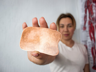 masseur holding a Gua sha copper scraper,masseur holding a Gua sha copper scraper