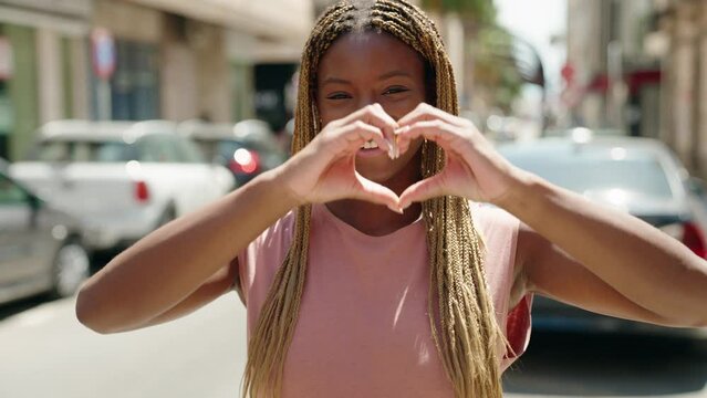African american woman smiling confident doing heart gesture with hands at street