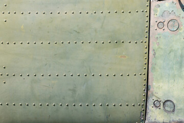 The exterior wall surface of a very old military green military helicopter. in the bright sunlight during the day