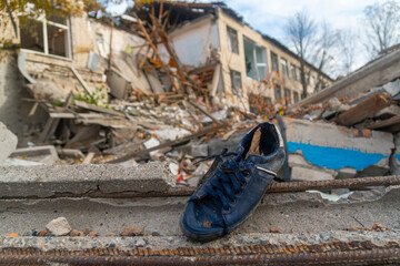 War in Ukraine. Russian invasion of Ukraine. A dark blue shoe lies near the ruined house. Destruction of infrastructure. Terror of the civilian population. War crimes