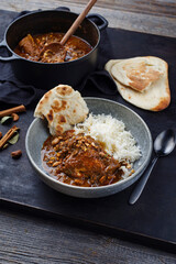 Traditional spicy Indian chicken Madras curry Rogan Josh with chicken, chapati bread and basmati rice served as close-up in a saucepan and a Nordic design bowl