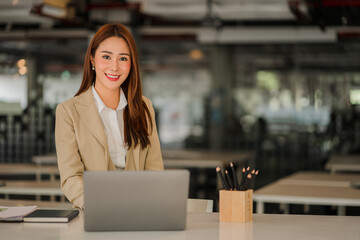 Happy smiling Asian businesswoman with laptop computer in modern office finance online accounting...