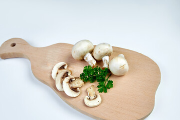 Sliced champignon mushrooms on a cutting board, white background